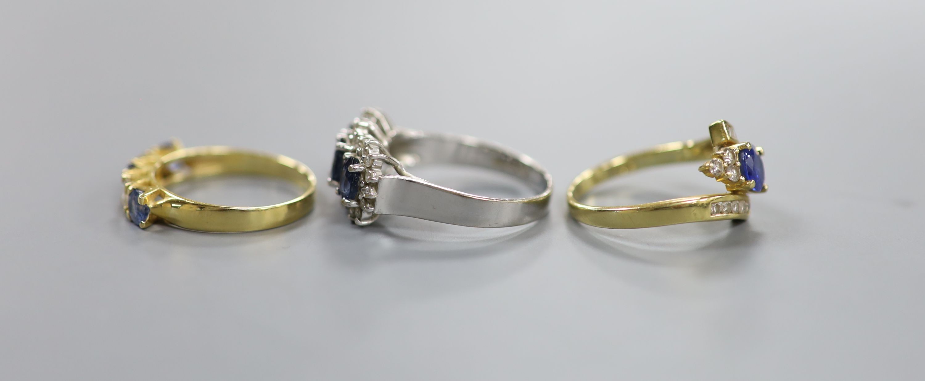 A modern 7560 white metal, sapphire and diamond set triple cluster ring, size Q/R and two other 18k, sapphire and diamond set dress rings, including half hoop, sizes O & N, gross weight 13.1 grams.